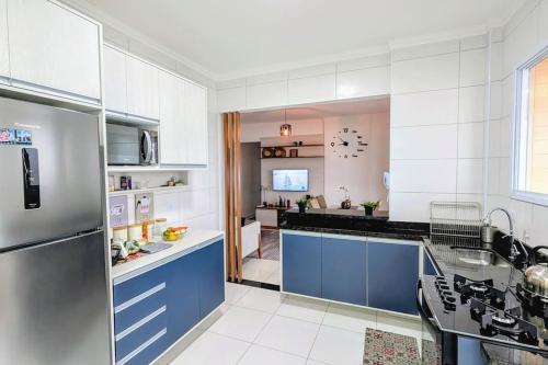 Apartamento Sol Nascente في برايا جراندي: مطبخ كبير مع الأجهزة الزرقاء والأبيض