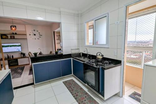 Apartamento Sol Nascente في برايا جراندي: مطبخ مع دواليب زرقاء وبيضاء وموقد