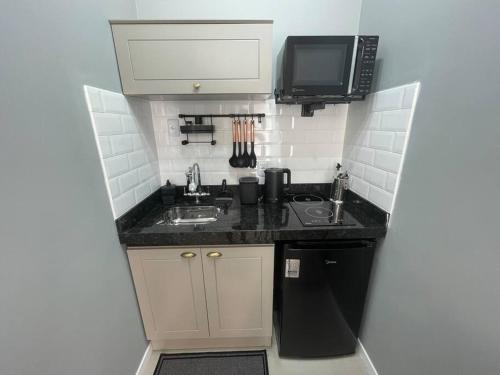 a small kitchen with a sink and a microwave at Loft Studio 101 em São José à 7km de Floripa in São José