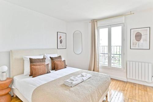 une chambre blanche avec un lit avec des serviettes dessus dans l'établissement Appartement spacieux Proche de la capitale - II, à Montreuil
