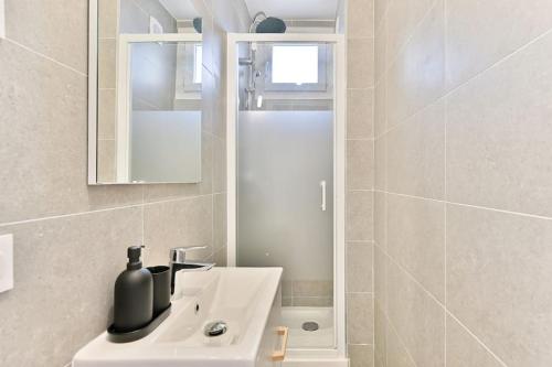 une salle de bain blanche avec un lavabo et un miroir dans l'établissement Appartement spacieux Proche de la capitale - II, à Montreuil