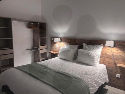 une chambre avec un lit avec des draps blancs et des oreillers dans l'établissement Gites L'atelier 1410, à Saint-Amand-les-Eaux