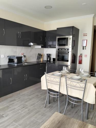 a kitchen with black cabinets and a table and chairs at Villa do Italiane in Estreito da Calheta