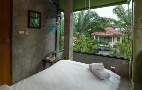a bedroom with a white bed and a large window at Krabi Green Hill Pool Villas in Ban Nong Thale
