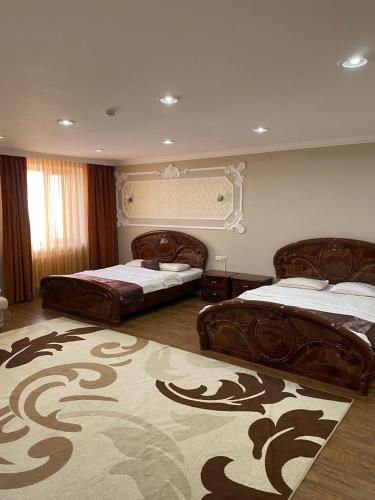 a bedroom with two beds and a rug at Sky Luxe Hotel in Astana
