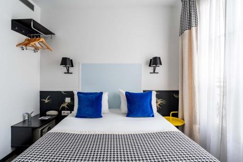 a bedroom with a large bed with blue pillows at Hotel George - Astotel in Paris