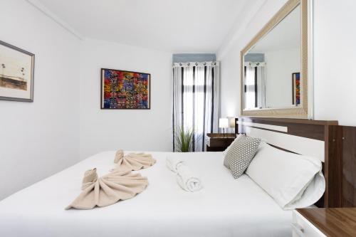 Dormitorio blanco con cama blanca y espejo en Urbanización Viña del Mar VIV, en Playa Fañabe