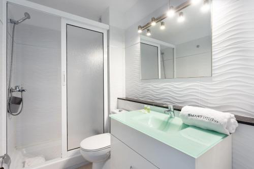 Un baño con lavabo, inodoro y espejo. en Urbanización Viña del Mar VIV, en Playa Fañabe