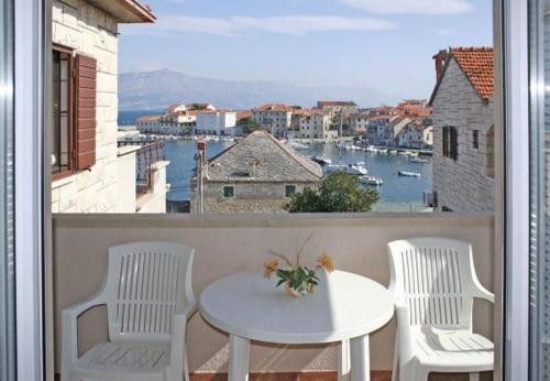 a table and chairs on a balcony with a view of a harbor at Apartments Paulina in Postira