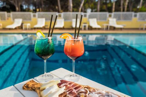two drinks sitting on a table next to a pool at Hotel Fiore Di Maggio in Villasimius