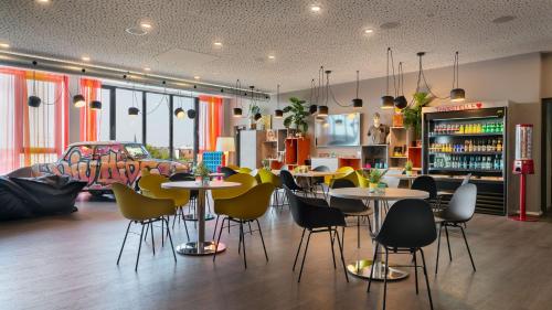 a restaurant with tables and chairs in a room at Holiday Inn - the niu, Hide Berlin Friedrichshain by IHG in Berlin