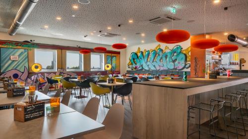 a restaurant with a bar and tables and chairs at Holiday Inn - the niu, Hide Berlin Friedrichshain by IHG in Berlin