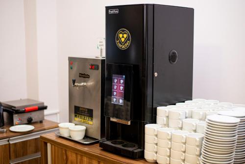 a coffee machine with a pile of cups on a counter at Cataratas Park Hotel e Eventos in Foz do Iguaçu