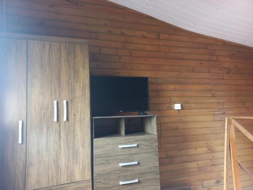a room with a tv and a wooden wall at Pousada Belas Praias Lofts da Riba in Imbituba