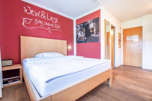 a bedroom with a large bed with a red wall at Hirschen Erlinsbach Swiss Quality in Erlinsbach
