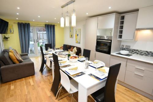 a kitchen and dining room with a white table and chairs at Chaucer House Holiday Home in Kent