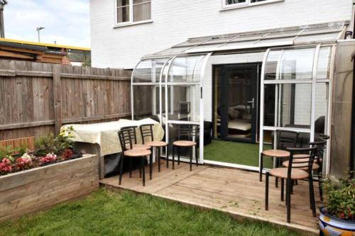 a patio with a table and chairs in a greenhouse at Chaucer House Holiday Home in Kent