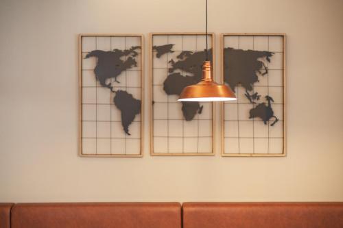 a bronze light hanging on a wall with a world map at Holiday Inn - the niu, Yen Hamburg City by IHG in Hamburg