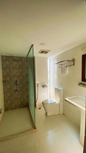 a bathroom with a shower and a toilet and a sink at La Vista Suites Sylhet in Sylhet