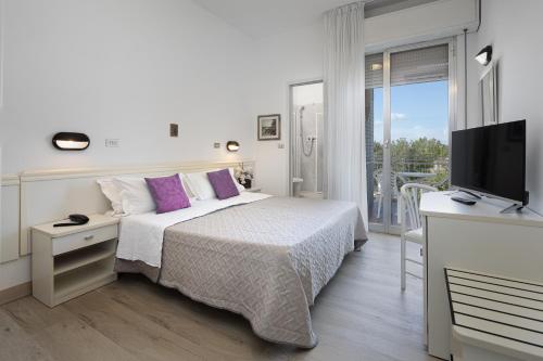biała sypialnia z łóżkiem i telewizorem w obiekcie Hotel Gioiello w Cesenatico