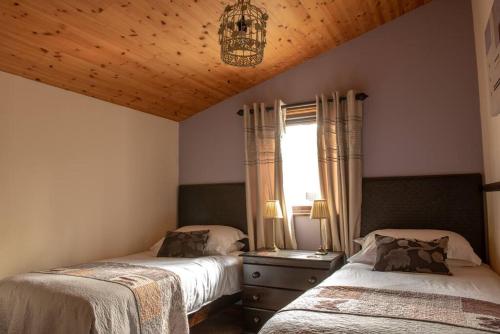 una camera da letto con due letti e un lampadario di Harvest 13 Lodge, Yellowtop Country Park a York