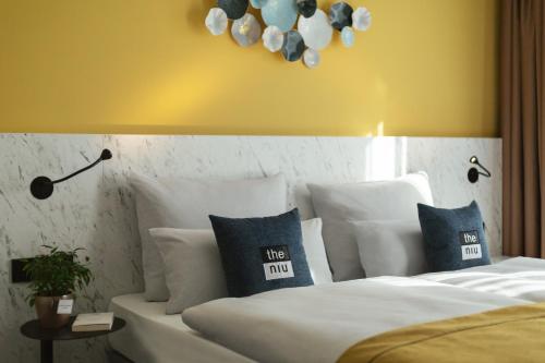a bedroom with a bed with white sheets and blue pillows at Holiday Inn - the niu, Kettle Stuttgart Vaihingen by IHG in Stuttgart