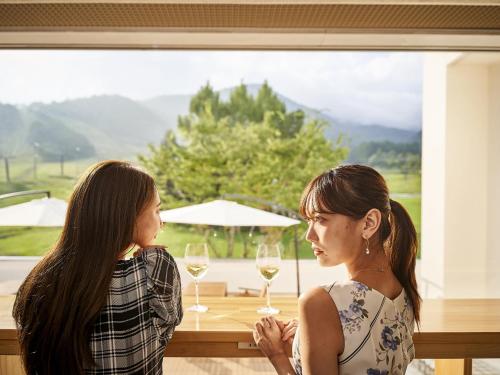 two women standing in front of a table with wine glasses at Hakuba Alps Hotel in Otari