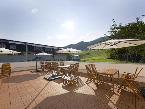 a group of tables and chairs with umbrellas on a roof at Hakuba Alps Hotel in Otari