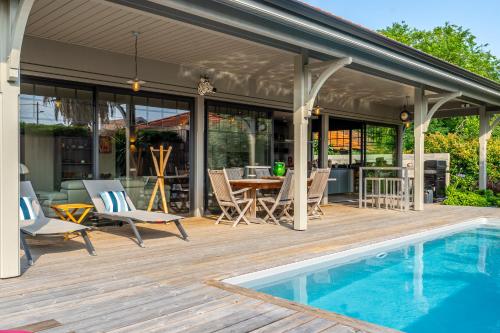 un patio avec une table et des chaises à côté d'une piscine dans l'établissement Superbe maison climatisée avec piscine, à La Teste-de-Buch