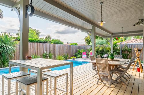 un patio avec une table et des chaises à côté d'une piscine dans l'établissement Superbe maison climatisée avec piscine, à La Teste-de-Buch