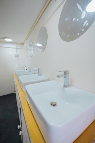 a white bathroom with three sinks and a mirror at 1950 Luangprabang Hostel in Luang Prabang