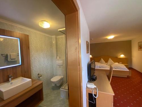 a bathroom with a sink and a toilet and a bed at Pension Edelweiss in Breitenbach