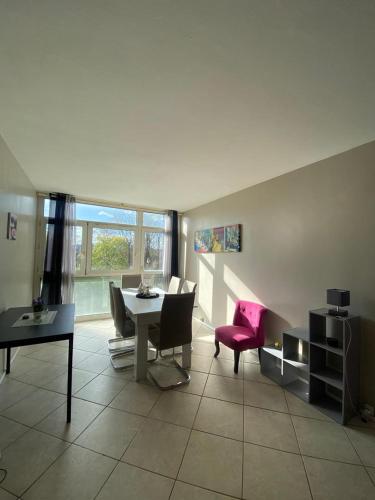 - un salon avec une table et une chaise rose dans l'établissement Évry : Grand Appartement 90m² pour 7 personnes, Évry-Courcouronnes