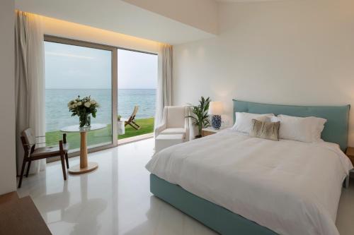 a bedroom with a large bed and a large window at Domes Miramare, a Luxury Collection Resort, Corfu - Adults Only in Moraitika