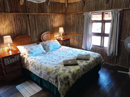 a bedroom with a bed with two pillows and a window at Kosi Bay Casitas in Manguzi