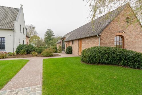 a brick house with a green lawn in front of it at Botanic Experience Holiday House in Oostkamp