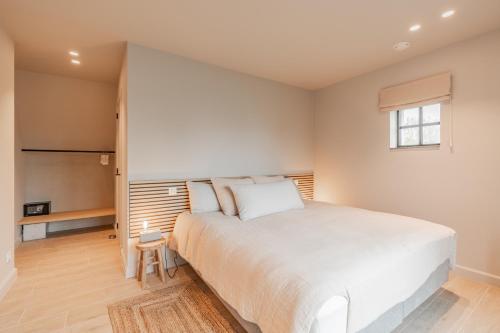a bedroom with a large white bed and a window at Botanic Experience Holiday House in Oostkamp