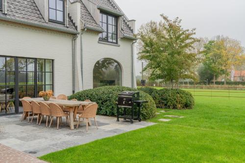 a patio with a table and chairs and a grill at Botanic Experience Holiday House in Oostkamp