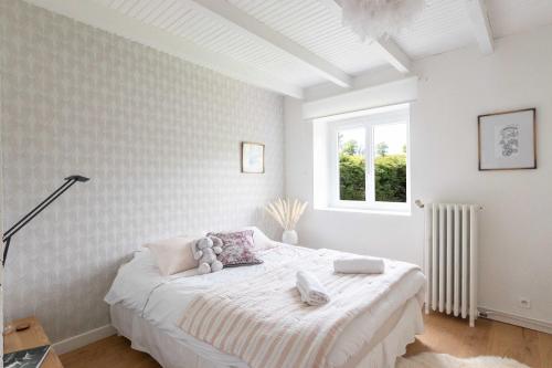 une chambre blanche avec un lit et une fenêtre dans l'établissement Maison Clos des Renauds, à Charbonnières