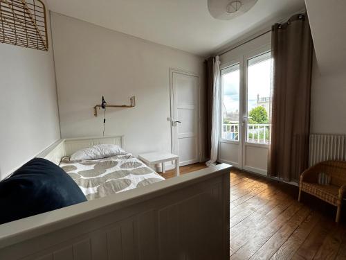 a bedroom with a bed and a large window at Rayon De Soleil in Courseulles-sur-Mer