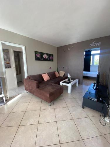 un salon avec un canapé marron et une table dans l'établissement Évry : Grand Appartement 90m² pour 7 personnes, Évry-Courcouronnes