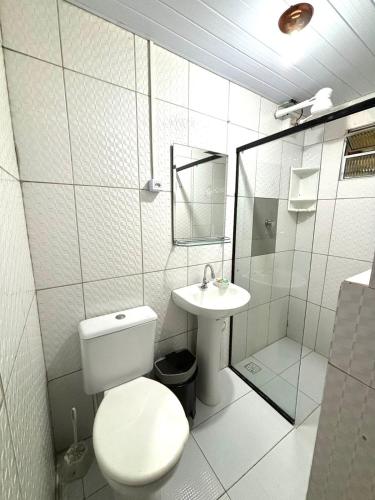 a white bathroom with a toilet and a sink at Pousada Porto de Paz - Noronha in Fernando de Noronha
