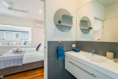 a bathroom with a bed and a sink and a mirror at Aaman & Cinta Luxury Villas in Byron Bay