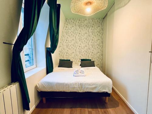 a small bedroom with a bed with a window at La Bonbonnière verte in Caen