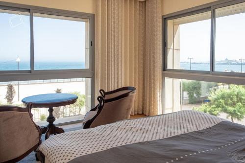 a bedroom with a bed and a table and windows at Marina Sea View Appartements in Casablanca