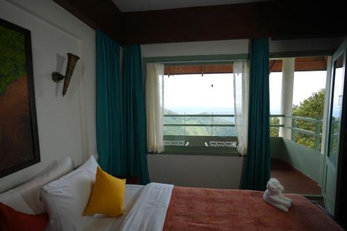 a bedroom with a bed and a window with a balcony at Blackberry Hills Munnar Nature Resort & Spa in Munnar