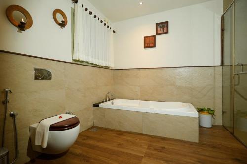 a bathroom with a bath tub and a toilet at Blackberry Hills Munnar Nature Resort & Spa in Munnar