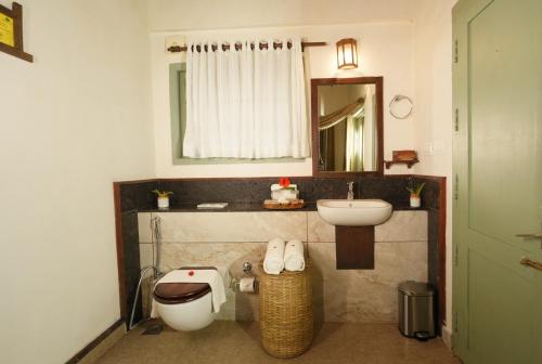a bathroom with a toilet and a sink and a mirror at Blackberry Hills Munnar Nature Resort & Spa in Munnar