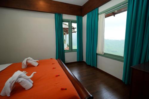 a bedroom with towels on a bed with windows at Blackberry Hills Munnar Nature Resort & Spa in Munnar