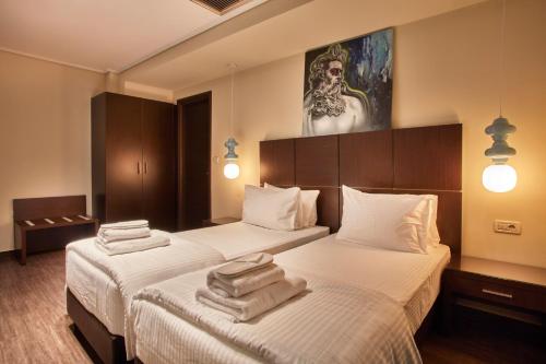 two beds in a hotel room with towels on them at Athens Way Pop Art Hotel in Athens